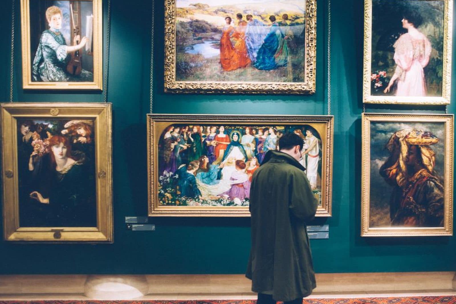 Un jeune homme observe des tableaux accrochés au mur d'un musée