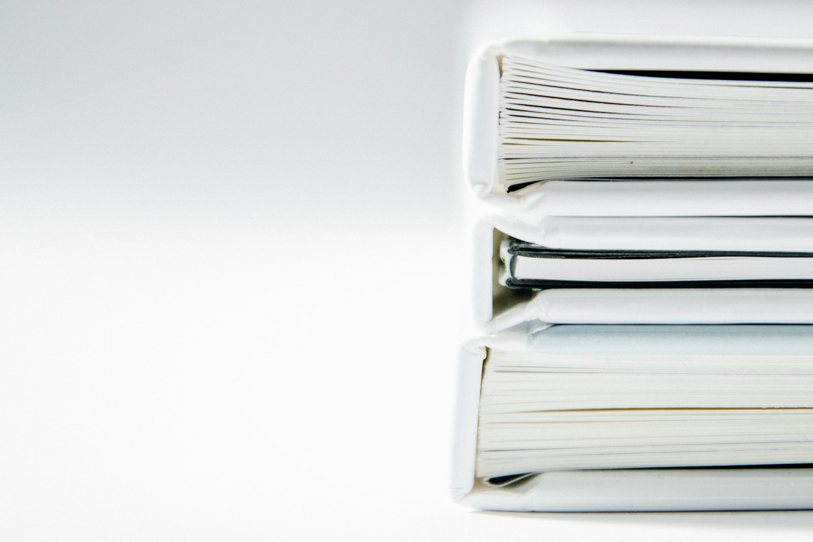 Une pile de classeurs épais posés sur un fond clair