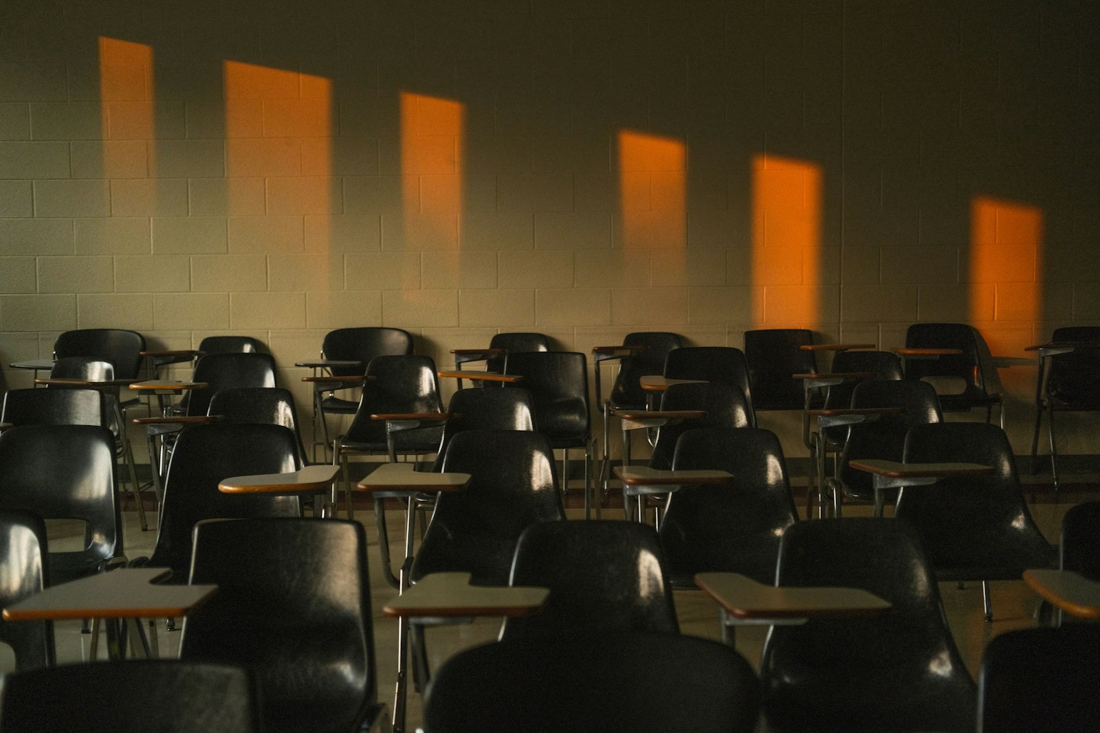 Une salle de classe vide, éclairée par une lumière rasante